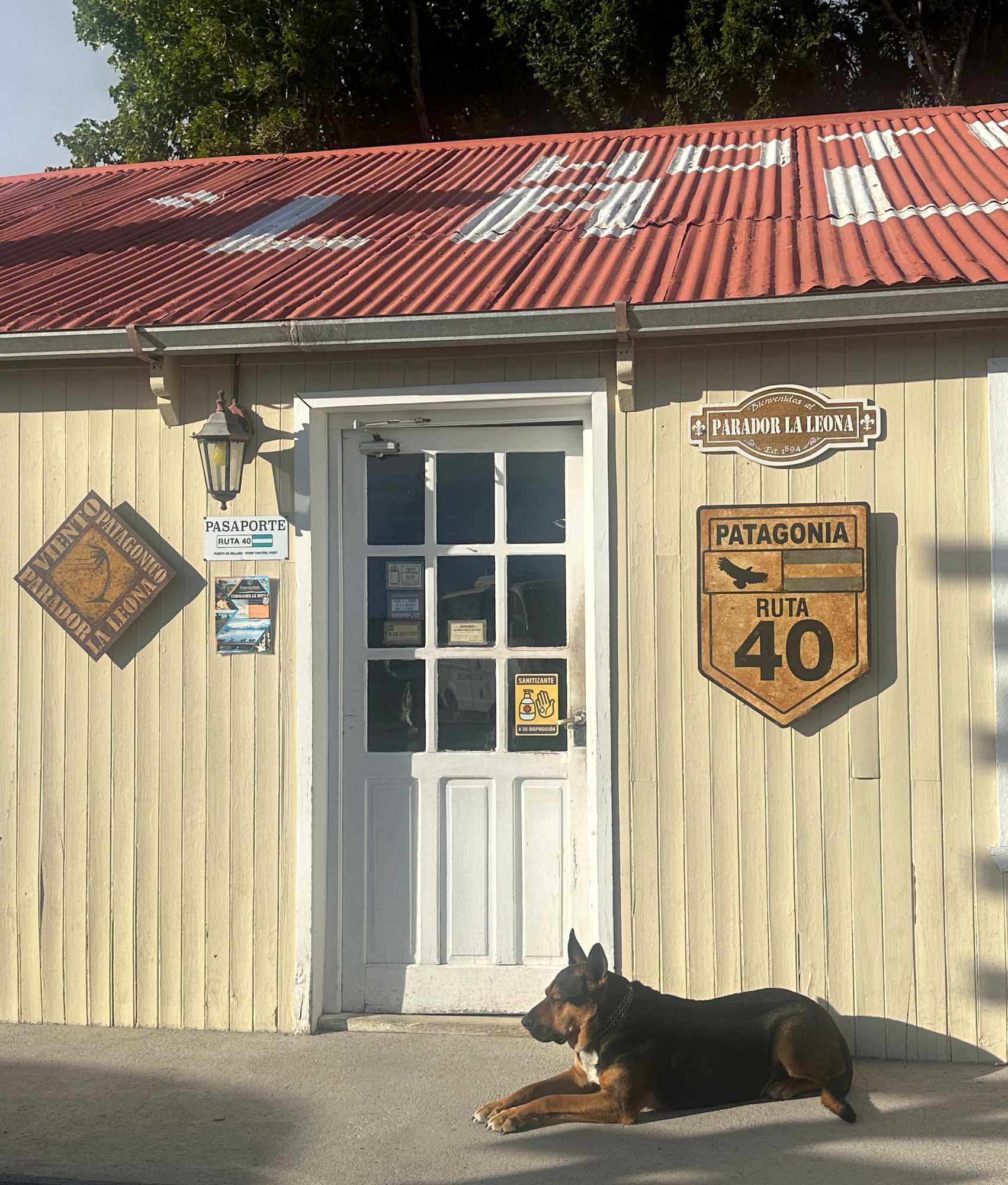 A charming rustic lodge building with cream-colored corrugated metal siding and a red metal roof