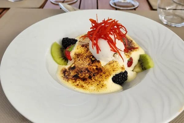 An elegantly plated fine dining dessert featuring a creamy custard or mousse base topped with fresh