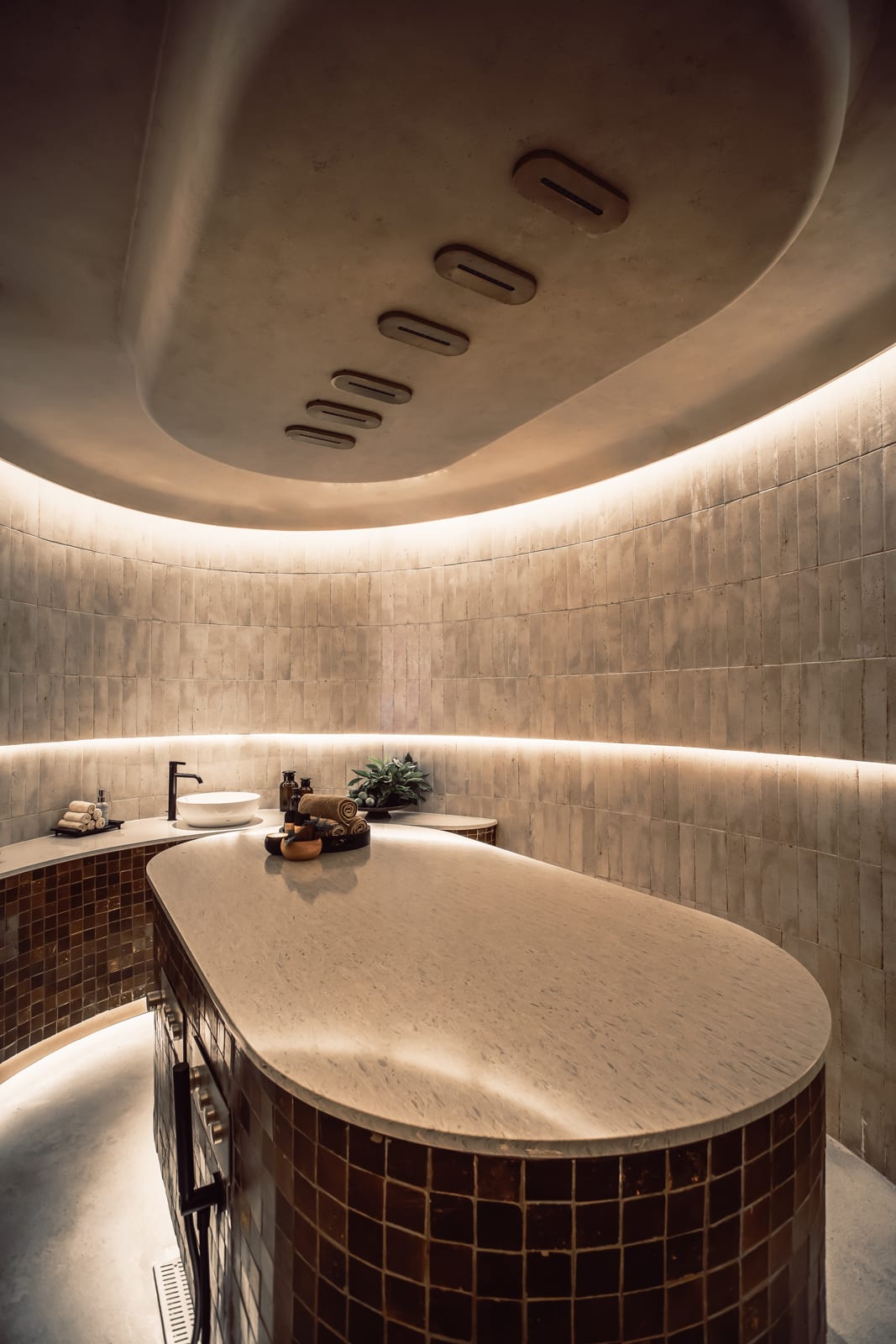 Luxurious spa bathroom with curved ceiling, marble soaking tub, and ambient lighting