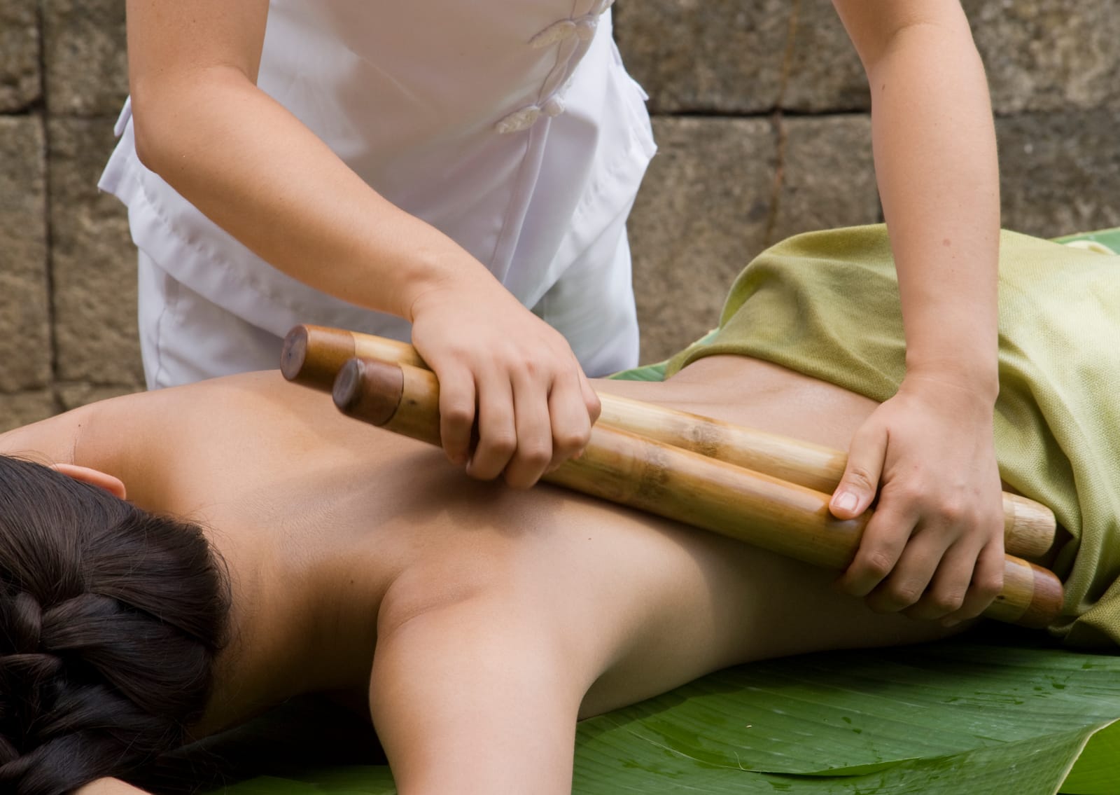 Bamboo massage treatment on back with wooden roller tool