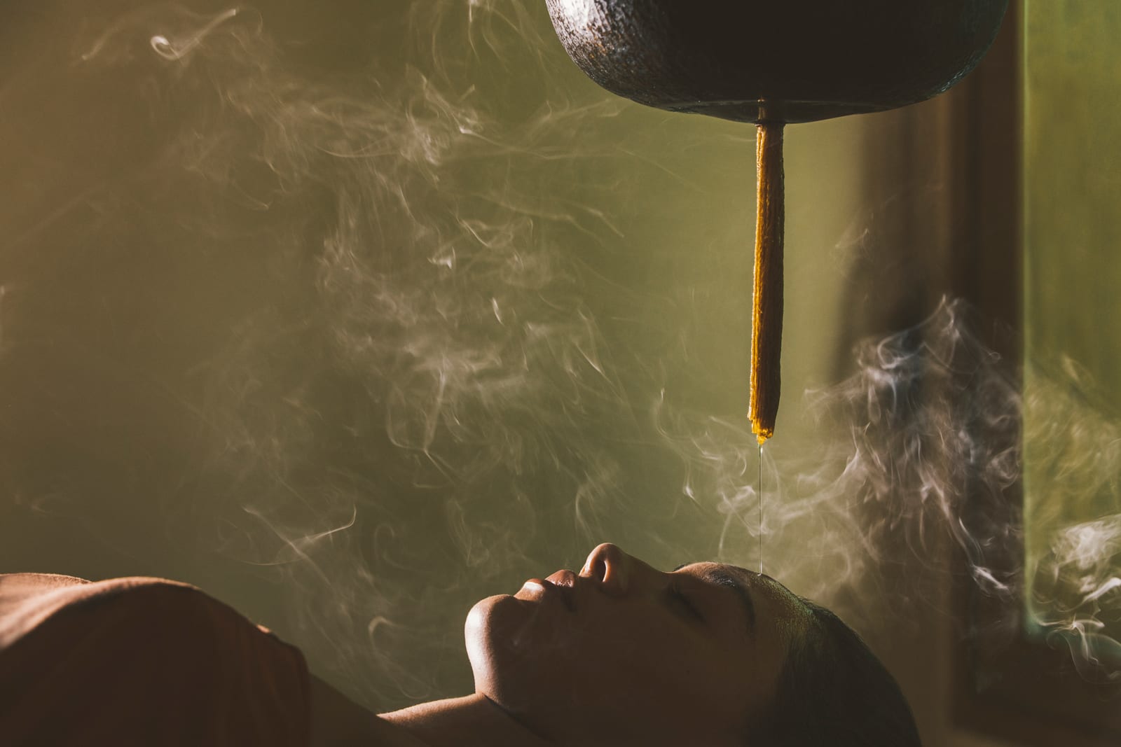 Person receiving steam sauna therapy treatment with overhead nozzle