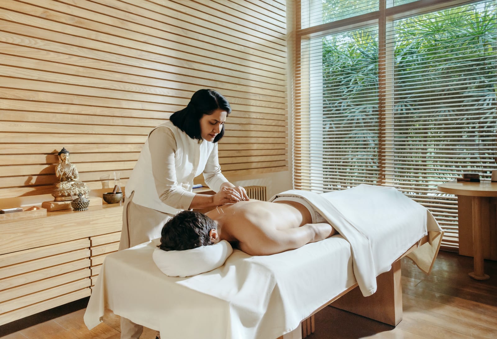 Massage therapist performing back massage on client in serene spa room with wood paneling