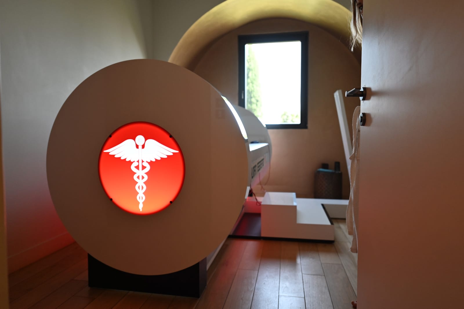 Illuminated medical caduceus symbol on spherical brown structure in modern medical facility hallway