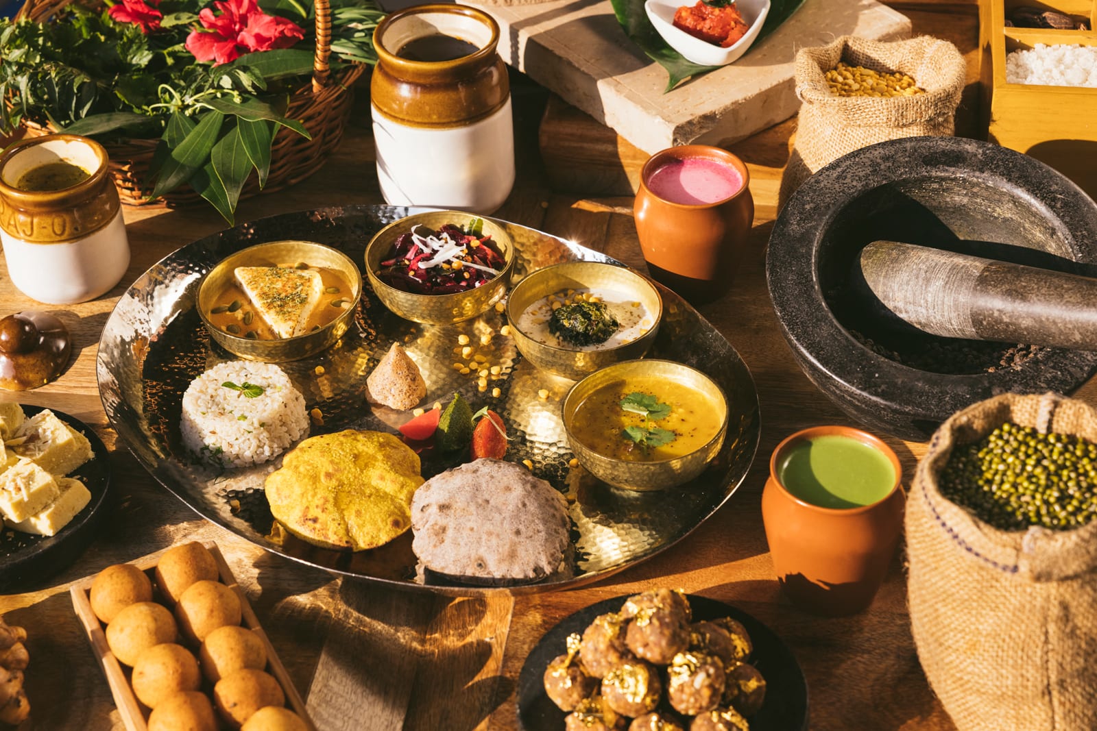 Indian cuisine spread with curries, breads, rice, and traditional stone mortar and pestle
