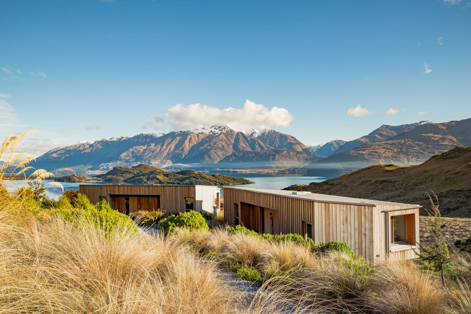 Modern corrugated metal lodge with mountain and lake views in New Zealand alpine landscape