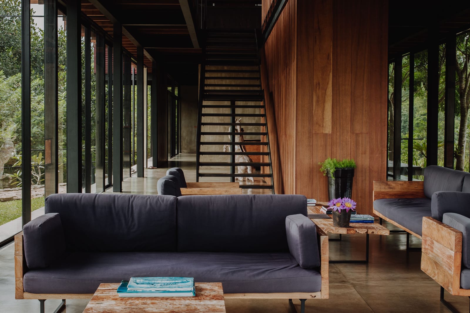 Modern living room with black sofa, wooden coffee table, and interior staircase in contemporary home