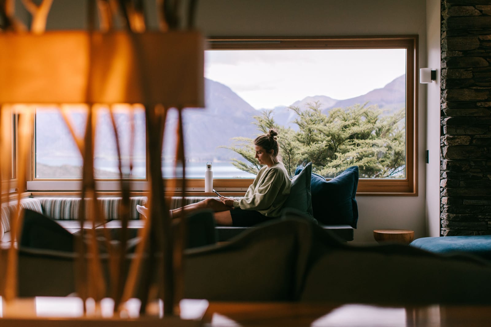 Person relaxing in outdoor infinity pool with mountain lake and snow-capped ranges in background at Aro Ha