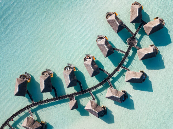 Overwater Bungalows Aerial View A stunning aerial view of thatched-roof overwater bungalows connected by wooden walkways