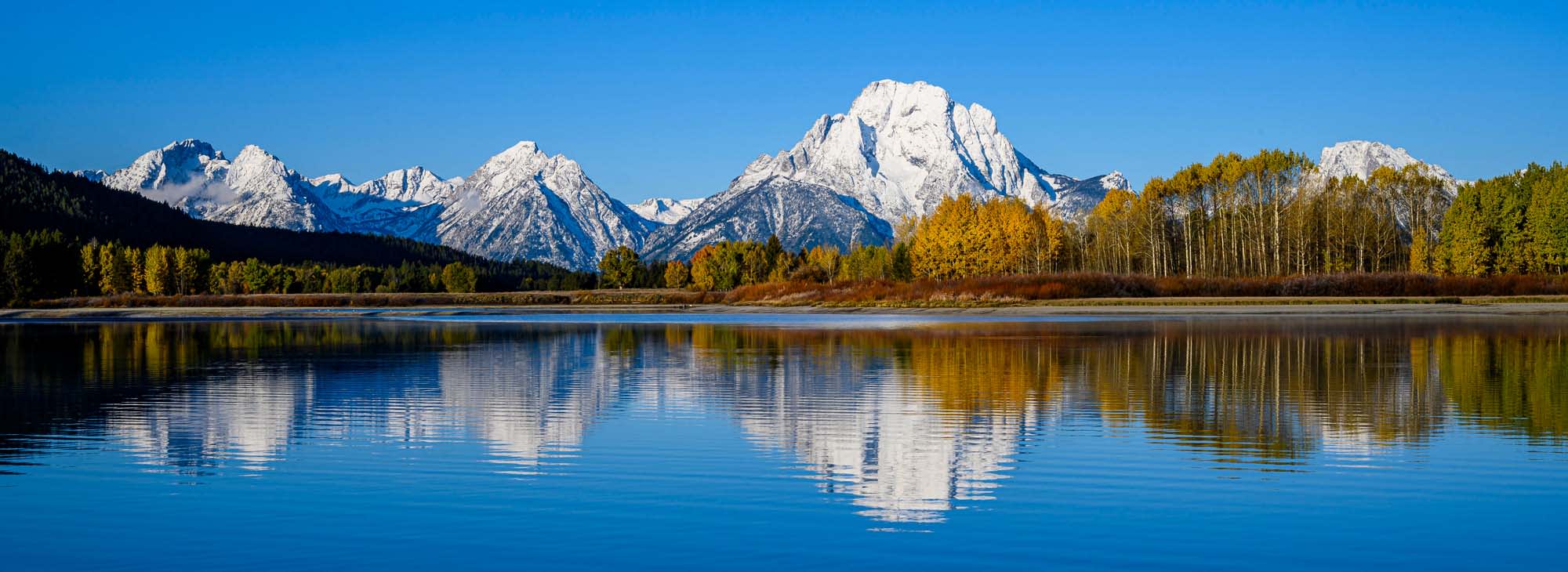 A stunning panoramic view of Oxbow Bend in Grand Teton National Park, featuring snow-capped