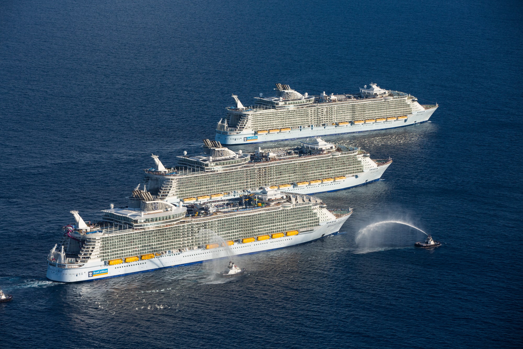 An aerial view of three massive cruise ships lined up in formation off the coast of Port