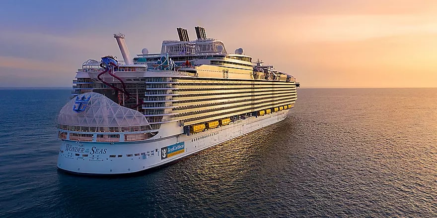 A massive modern cruise ship photographed from the water during golden hour, showcasing its