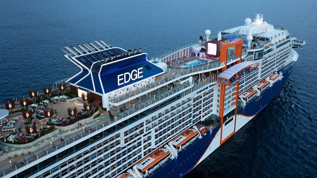 celebrity-edge A modern luxury cruise ship sails peacefully through calm tropical waters during a spectacular golden sunset, with vibrant orange and pink clouds reflected on the sea's surface. The vessel's contemporary design and white superstructure are illuminated by the warm evening light.