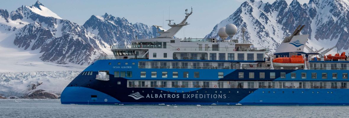 An Albatros Expeditions cruise ship navigating through a dramatic polar seascape with snow-capped