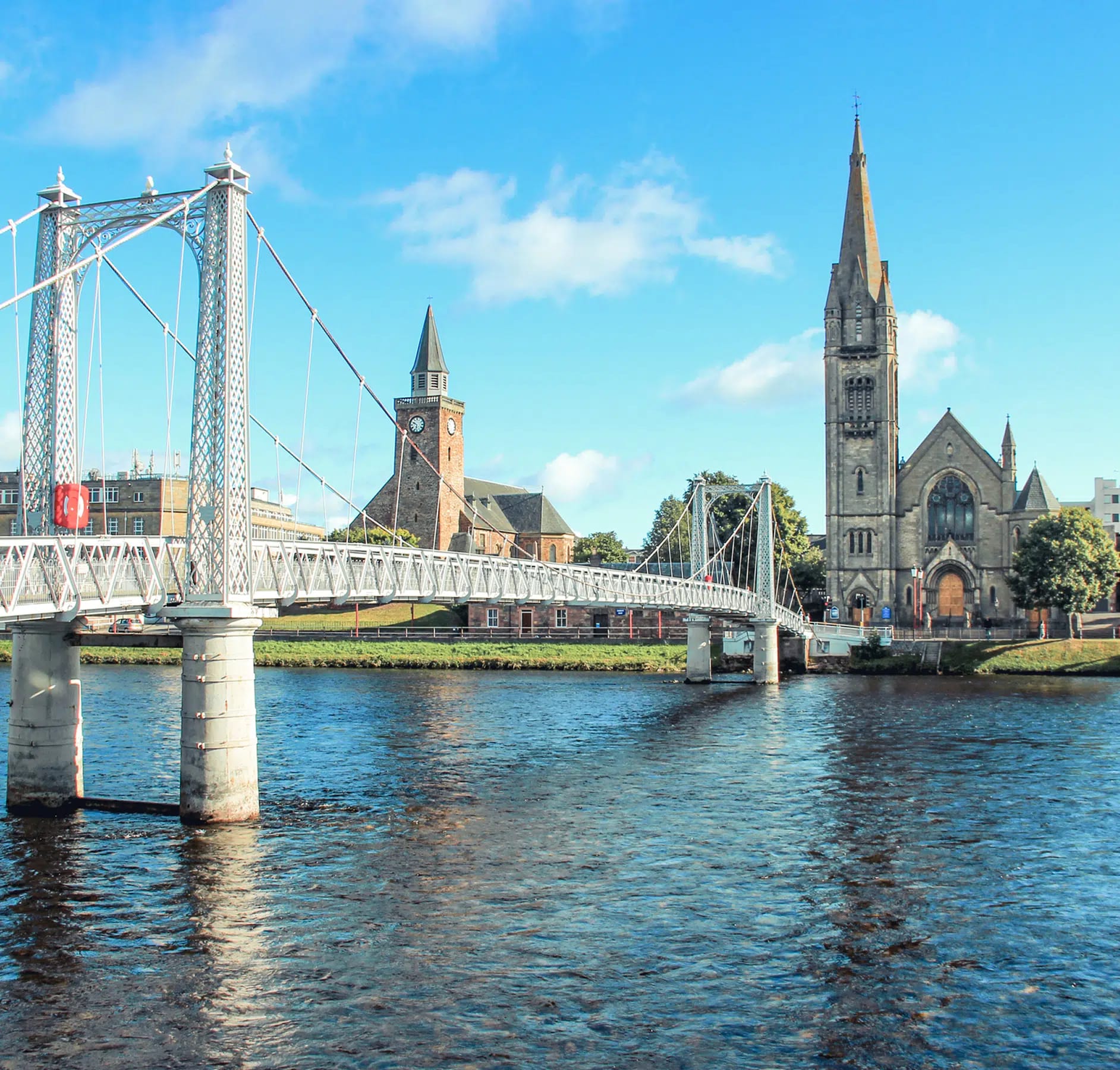 A picturesque view of the white ornamental Albert Bridge spanning the River Ness in Inverness