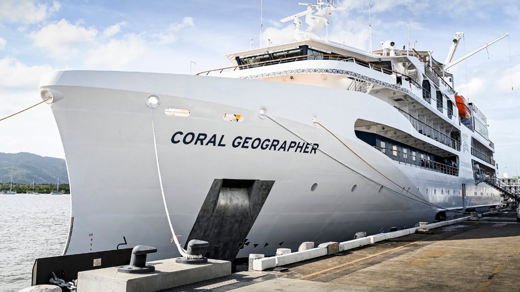 Coral Geographer Cruise Ship Docked The Coral Geographer, a luxury expedition cruise ship, is moored at a tropical port
