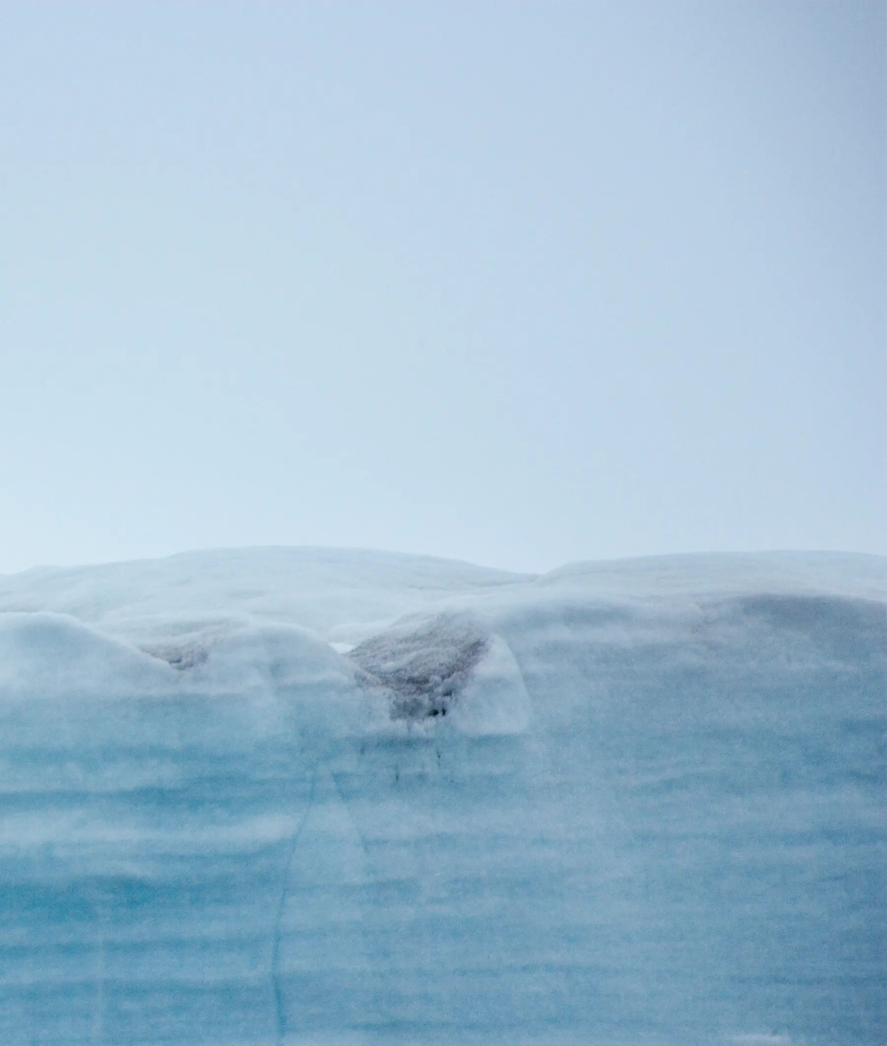 A striking photograph of a massive blue glacier or iceberg with layered ice formations rising above
