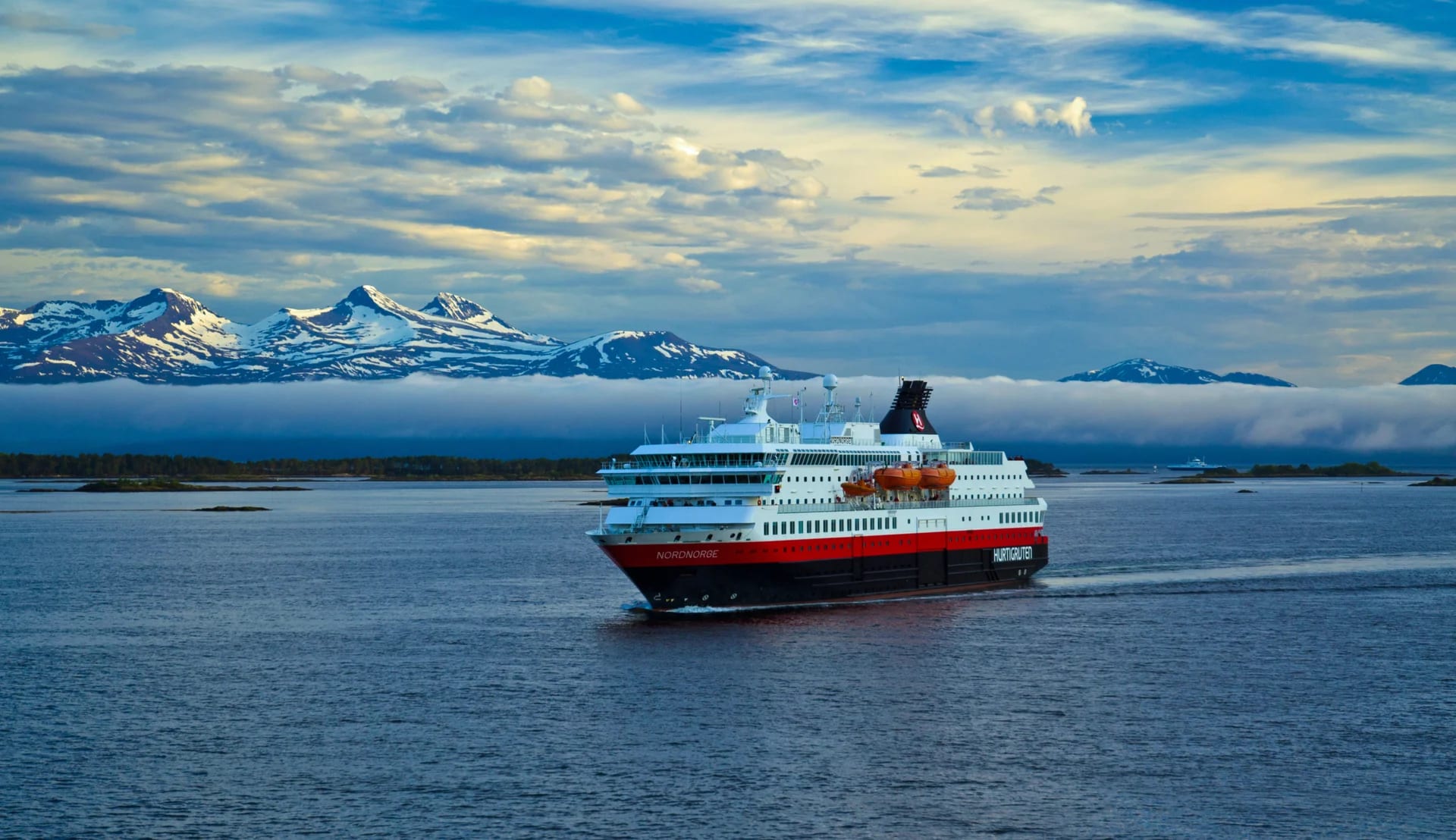 Hurtigruten Cruise Ship in Norwegian Fjords A Hurtigruten cruise ship sailing through a scenic Norwegian fjord landscape, with snow-capped mountains in the background and misty waters surrounding the vessel.