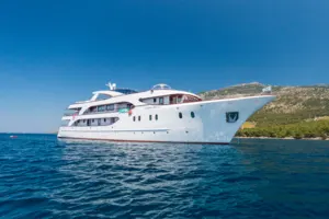 A striking white multi-deck motor yacht with sleek modern design anchored in calm blue