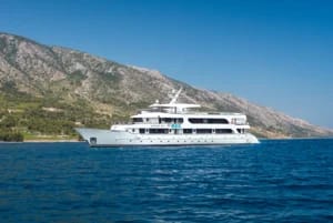 A pristine white luxury motor yacht anchored in crystal-clear turquoise Mediterranean waters with