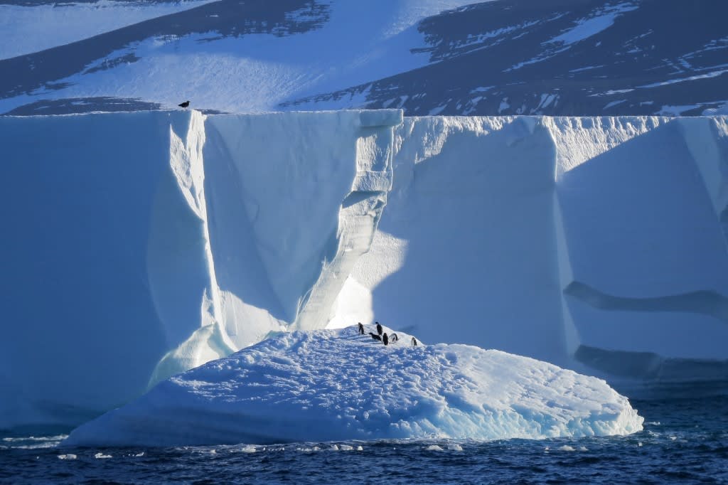 A stunning massive iceberg with towering white walls and deep blue crevasses rises dramatically
