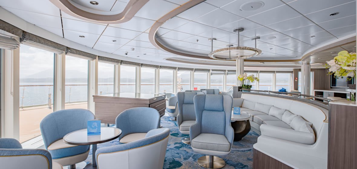 A sophisticated and contemporary lounge area aboard a luxury cruise ship featuring floor-to-ceiling