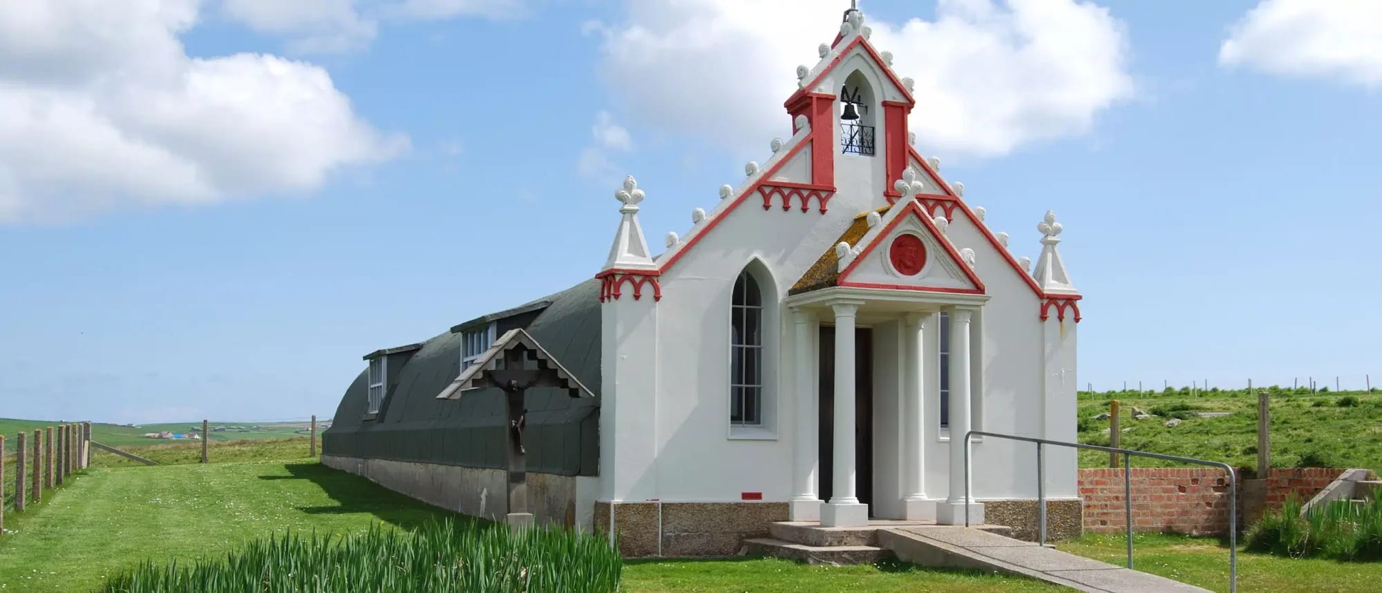 A charming small chapel featuring distinctive red and white Victorian architecture sits isolated