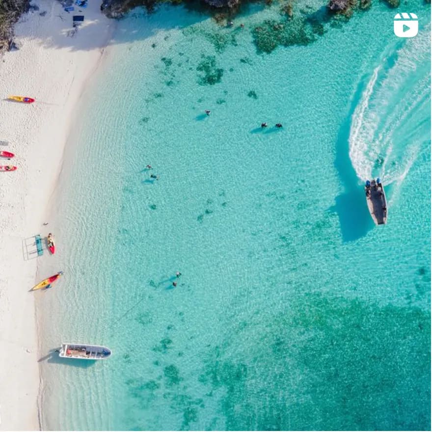 Tropical Beach Paradise with Speedboats An aerial view of a pristine tropical beach with crystal-clear turquoise waters, white sand