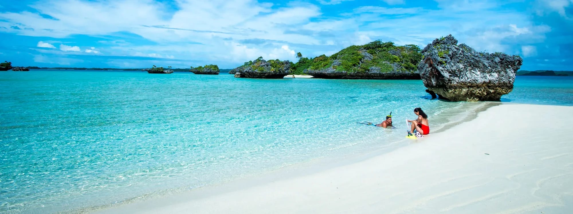 Tropical Island Beach Paradise with Crystal Waters A pristine white sand beach with turquoise crystal-clear waters featuring a family enjoying