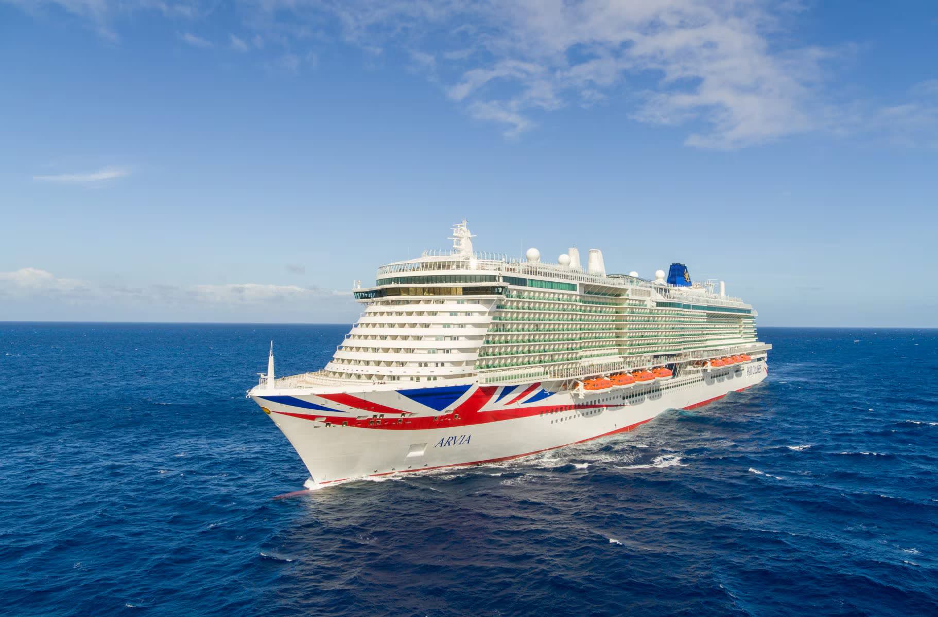 arviashipatseajpg1688460616148image18221200high A modern large cruise ship with distinctive white hull and Union Jack-inspired livery sails through deep blue ocean waters under clear skies.