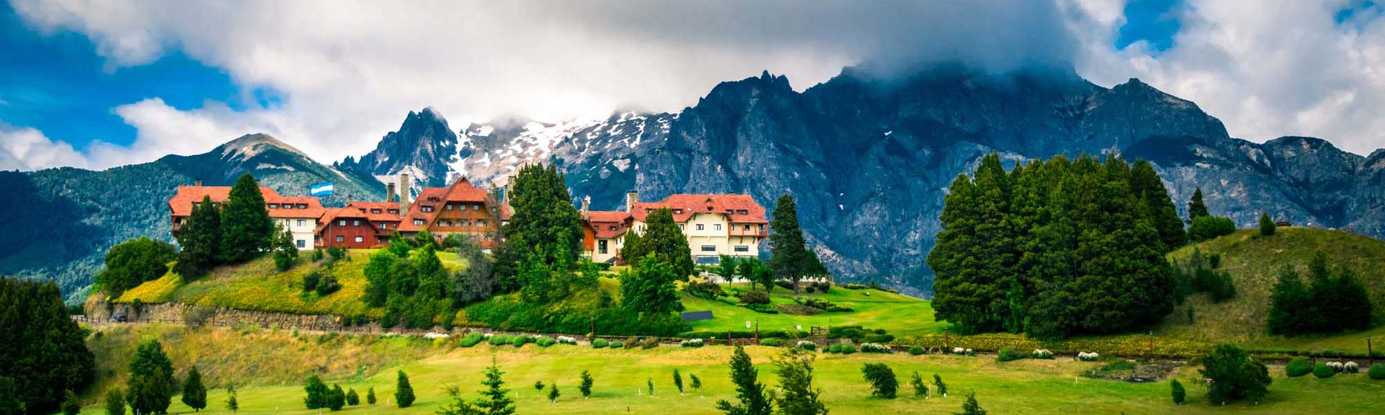 Alpine Castle Overlooking Swiss Mountain Valley A striking castle with distinctive orange-red roofs nestled on a hillside amid lush green meadows, surrounded by dramatic snow-capped Alpine peaks and dense evergreen forests. The picturesque setting exemplifies classic Swiss alpine architecture and landscape.