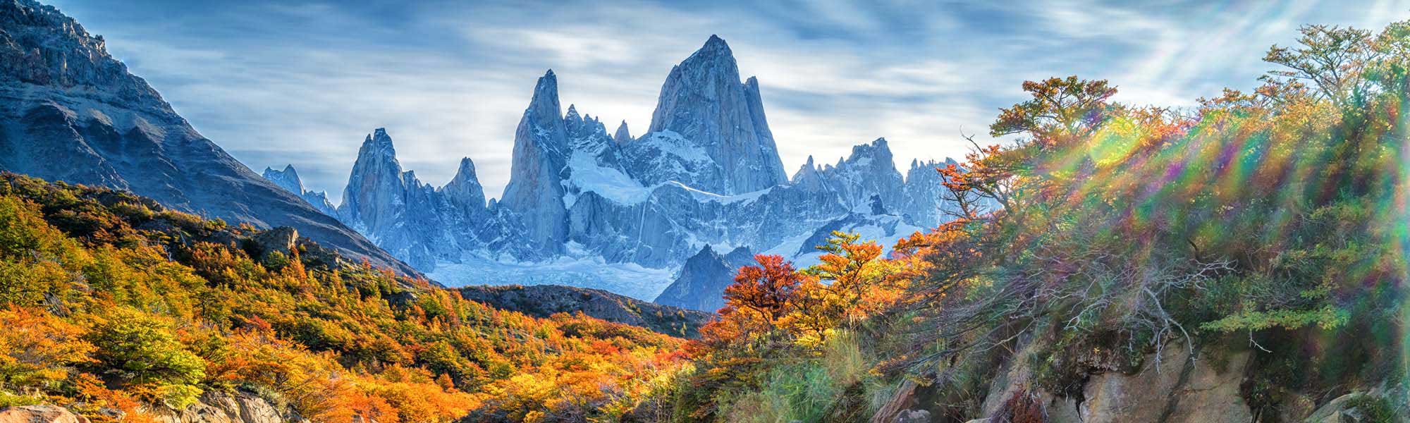 A stunning landscape featuring the iconic granite peaks of Mount Fitz Roy framed by vibrant autumn