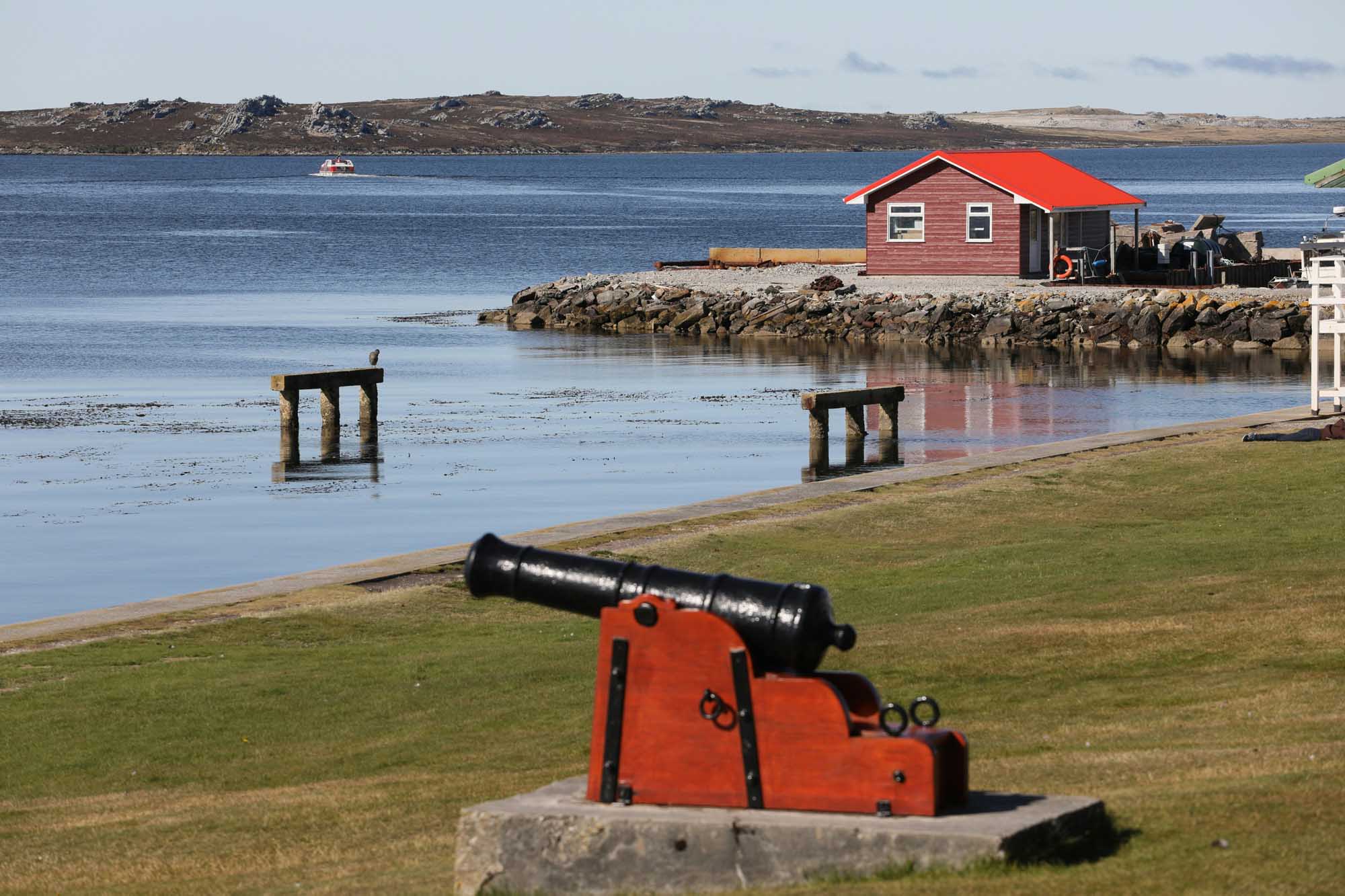 A picturesque Arctic coastal settlement featuring a distinctive red-roofed boathouse perched on