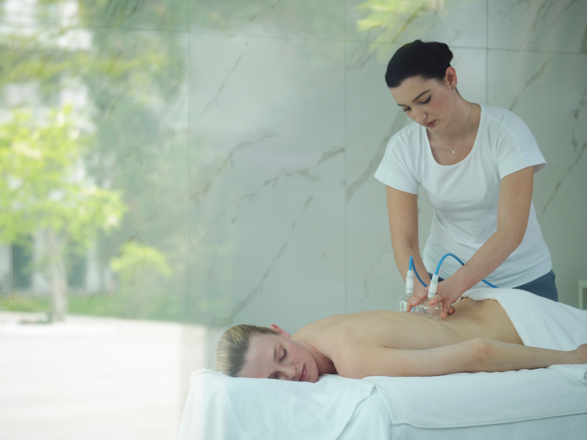 240501_Chenot Palace Weggis_DSCF7151 Therapist performing ultrasound therapy treatment on client's back in spa setting