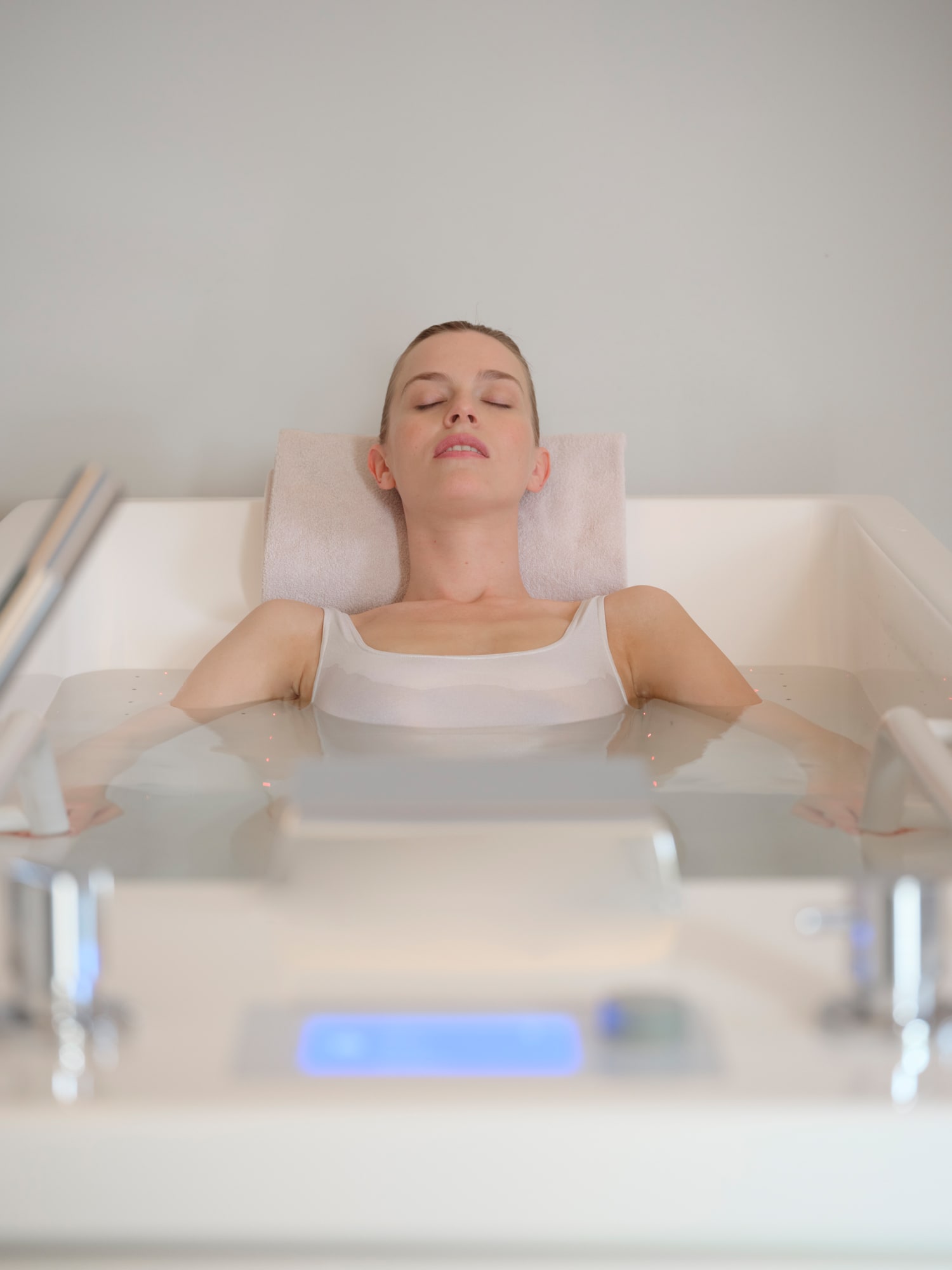 Woman relaxing in a spa bath with closed eyes and neck pillow support