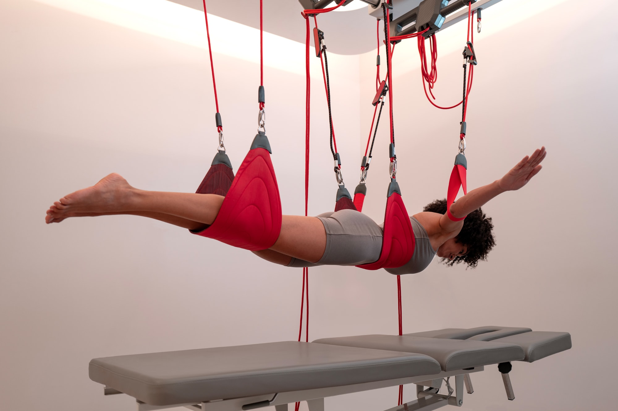 240505_Chenot Palace Weggis_L1023468 Person performing aerial yoga suspension exercise with red straps and carabiners