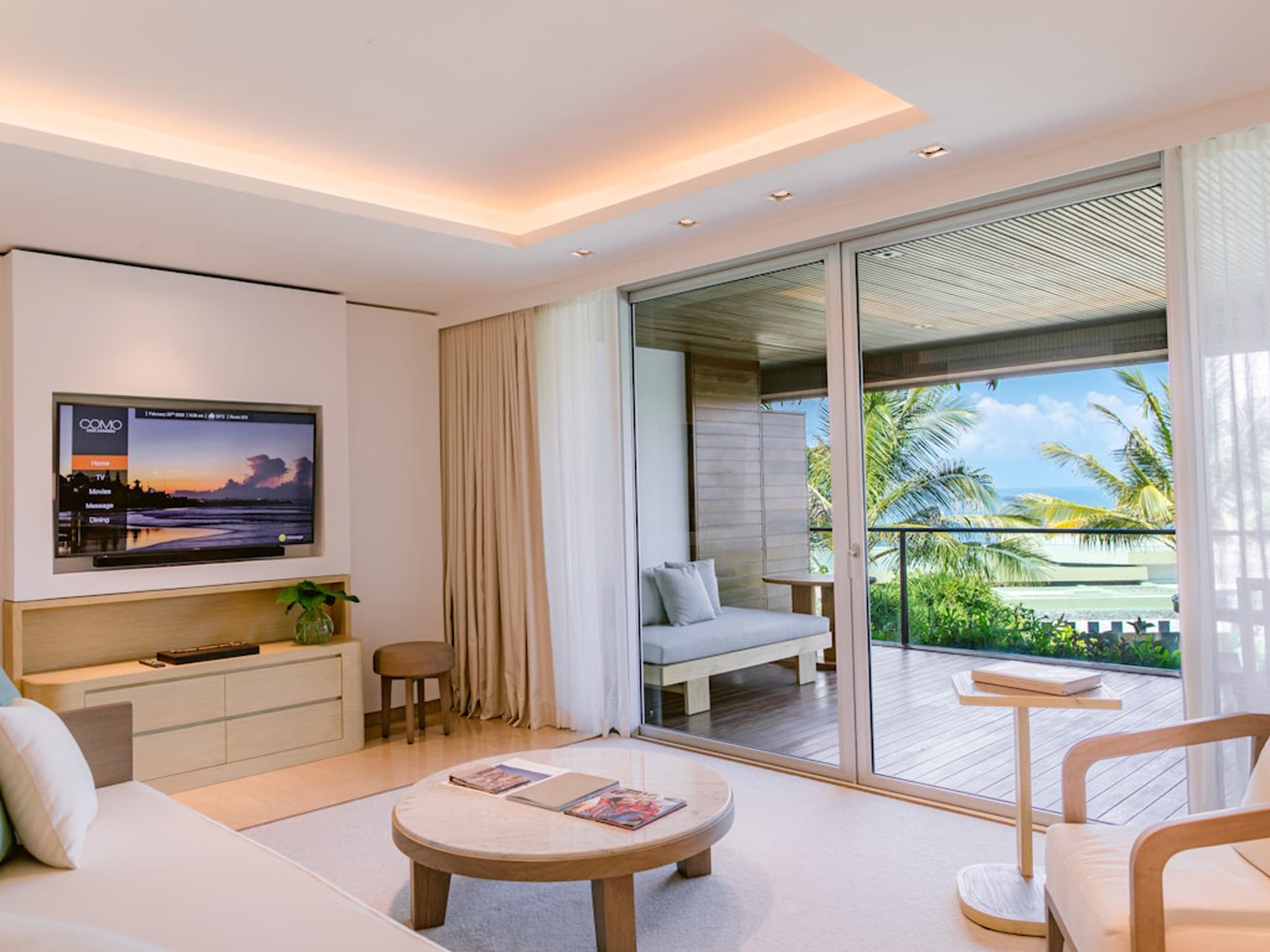 3I1A6125-1_Medium Luxury resort bedroom with flat-screen TV, ocean view through sliding glass doors, and modern wood furnishings