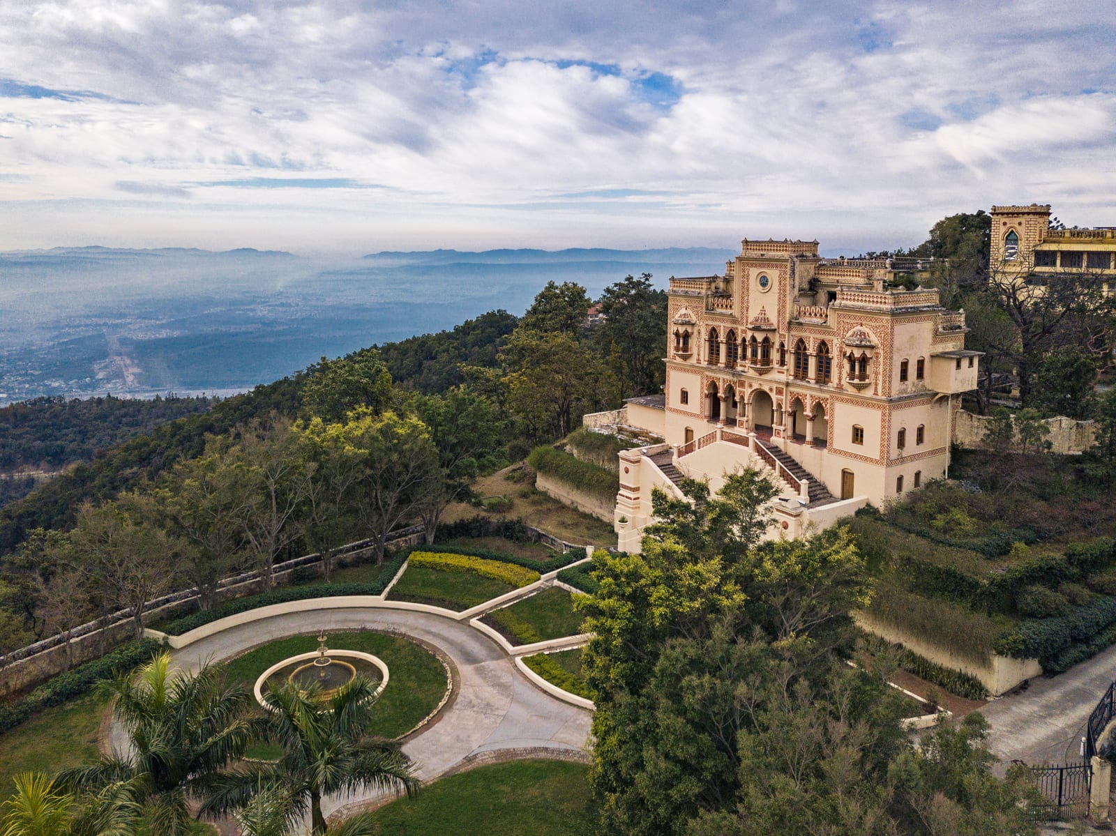 Ananda_Palace and Valley Neogothic palace on hilltop overlooking lake and forested valley with manicured gardens