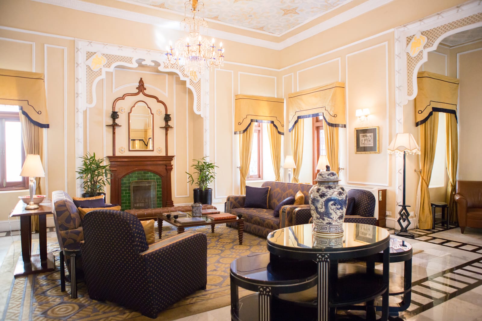 Ananda_Viceregal Lounge 1 Elegant hotel lounge with cream and gold decor, fireplace, and crystal chandelier