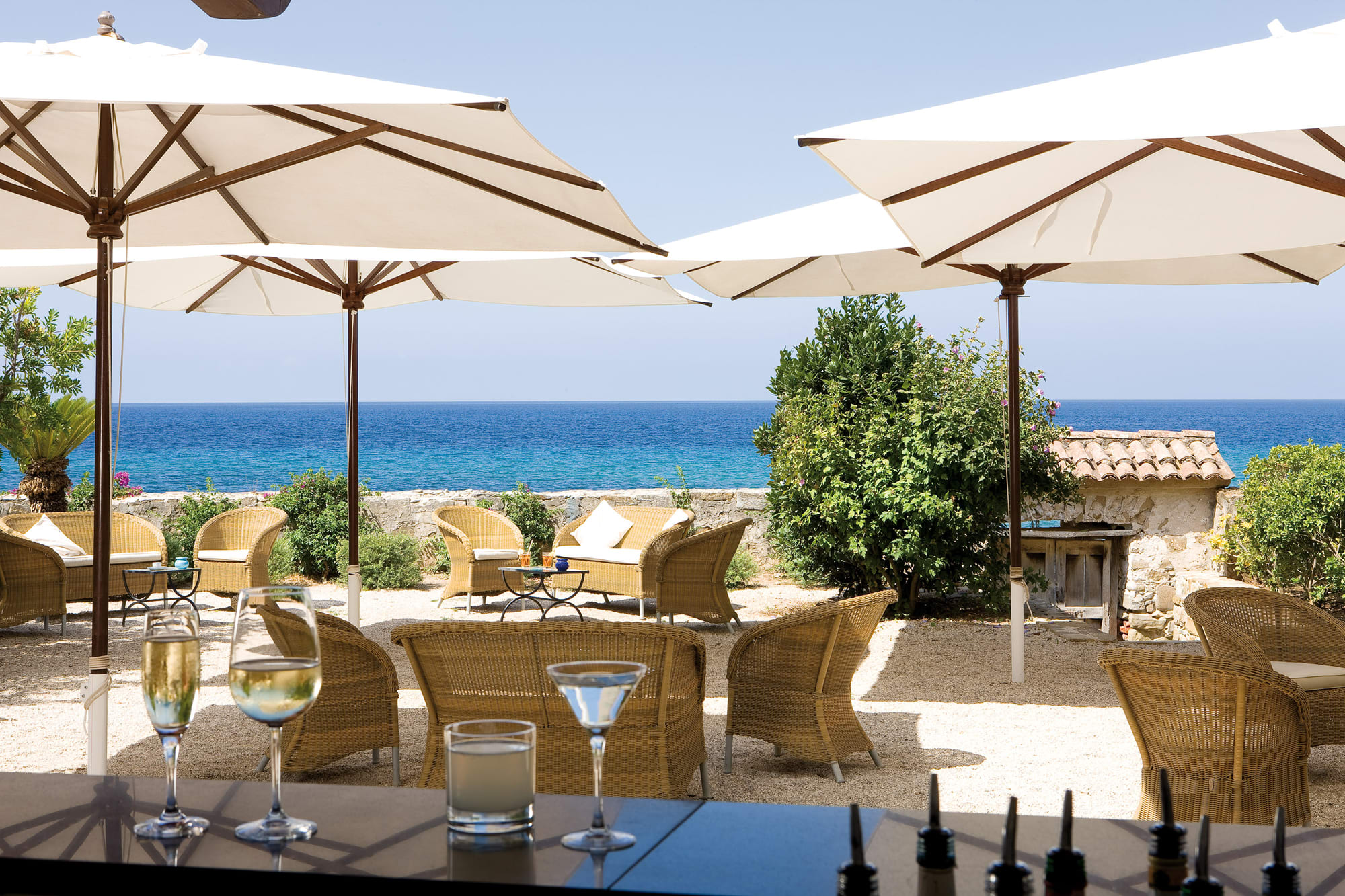 Copy of Copy of Bar Coastal terrace with cream umbrellas, wicker chairs, and Mediterranean sea view