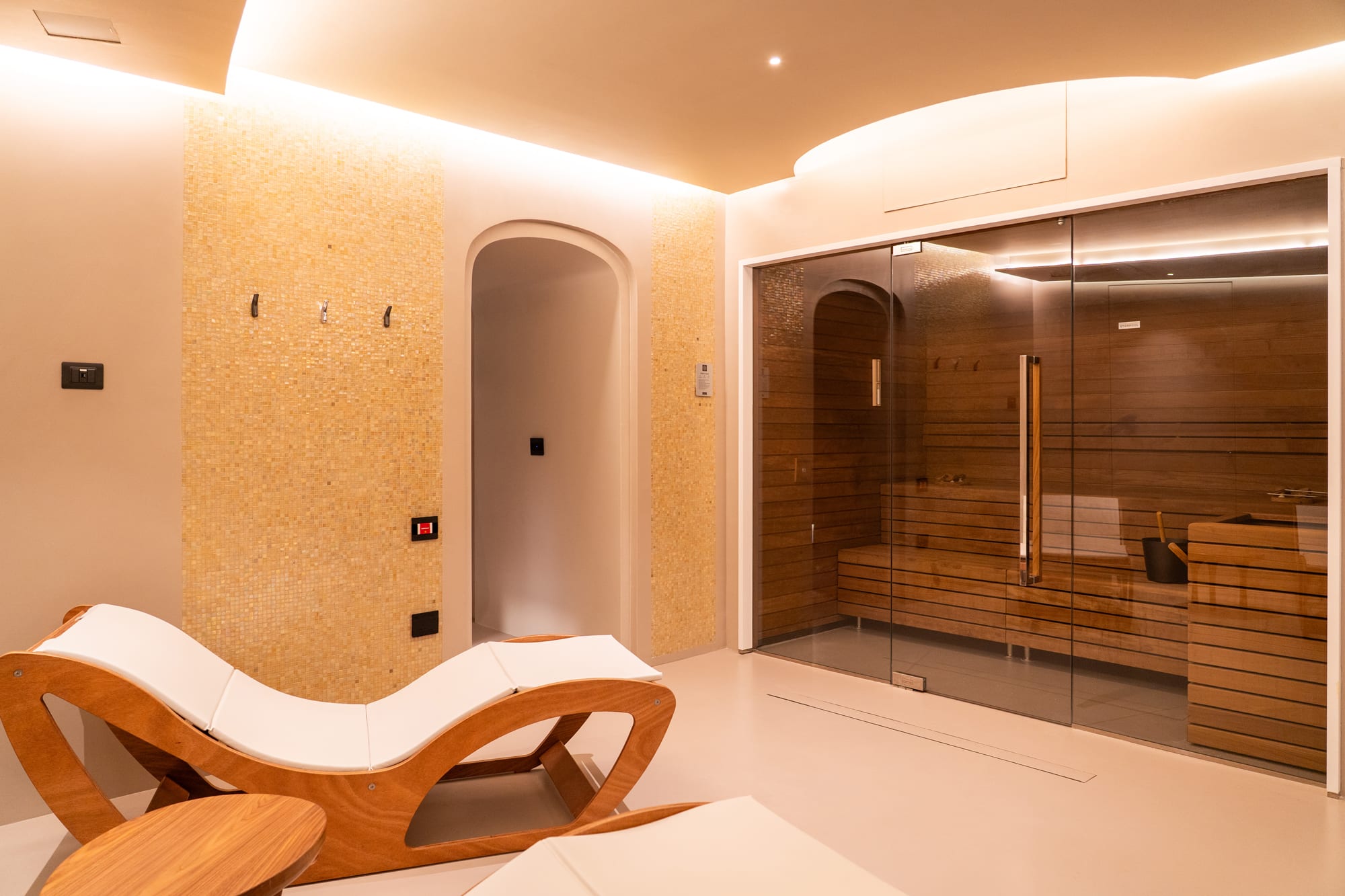Modern spa area with sauna, wooden lounge chair, and warm ambient lighting