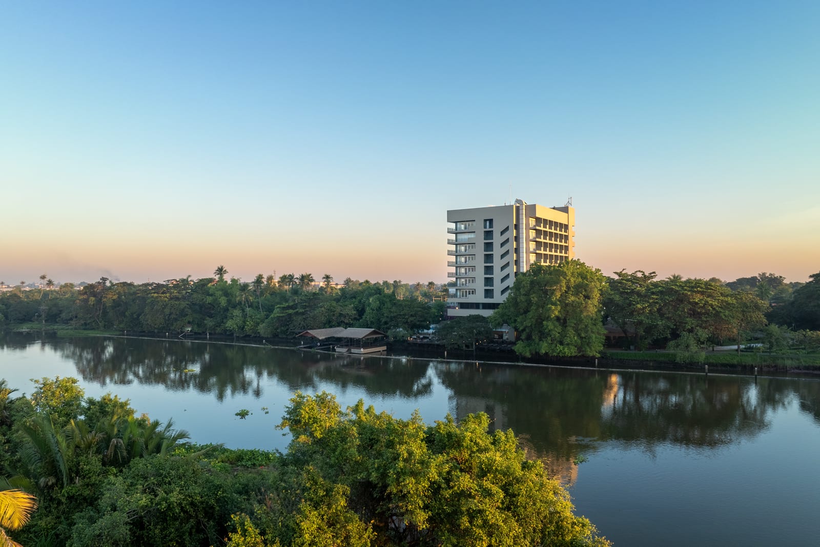 DJI_0881-HDR (1) Modern residential building with yellow facade on riverside surrounded by tropical vegetation at sunset