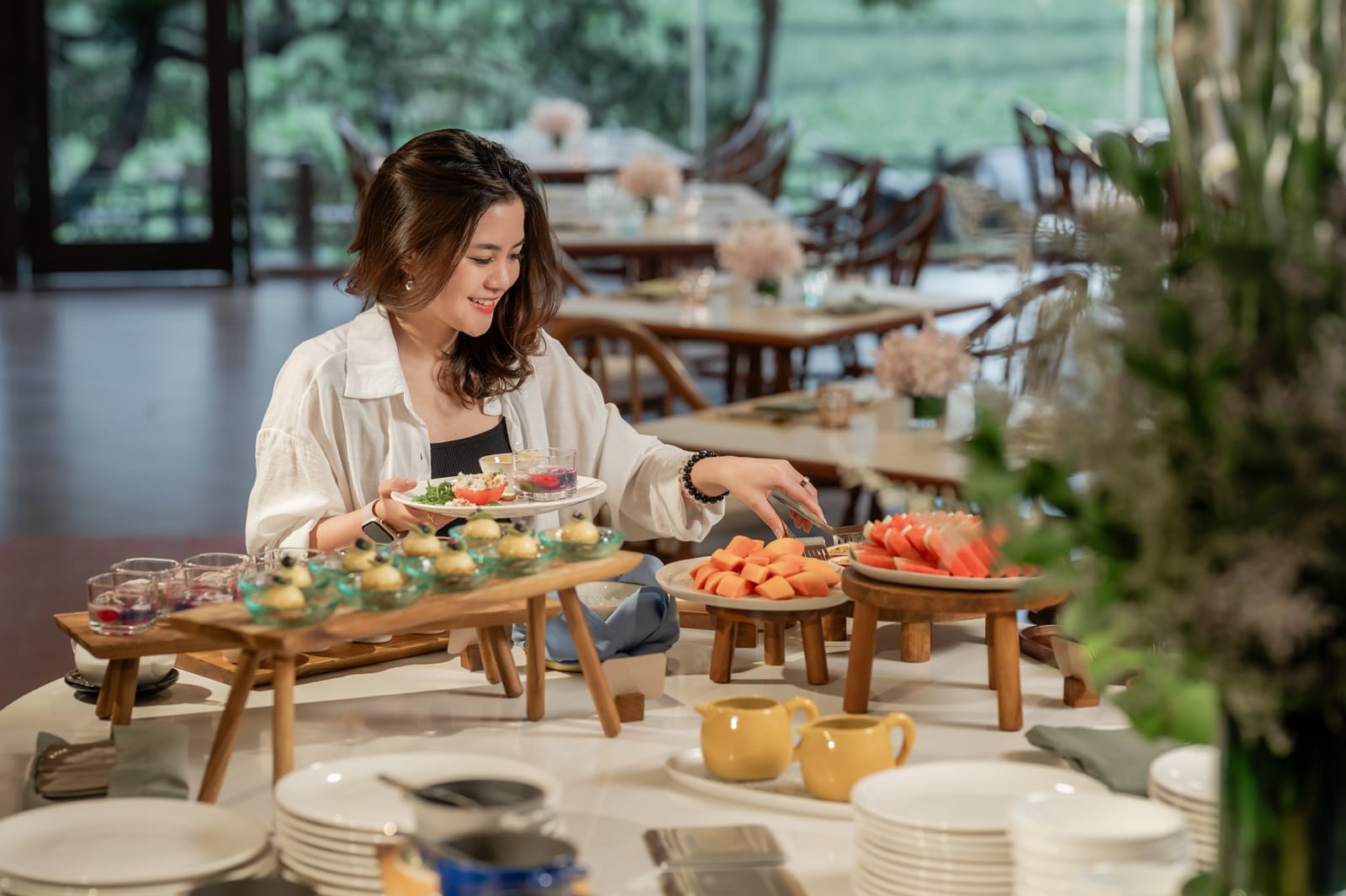 KTZ_6958 Woman arranging appetizers and fruit on wooden serving tables in modern dining room
