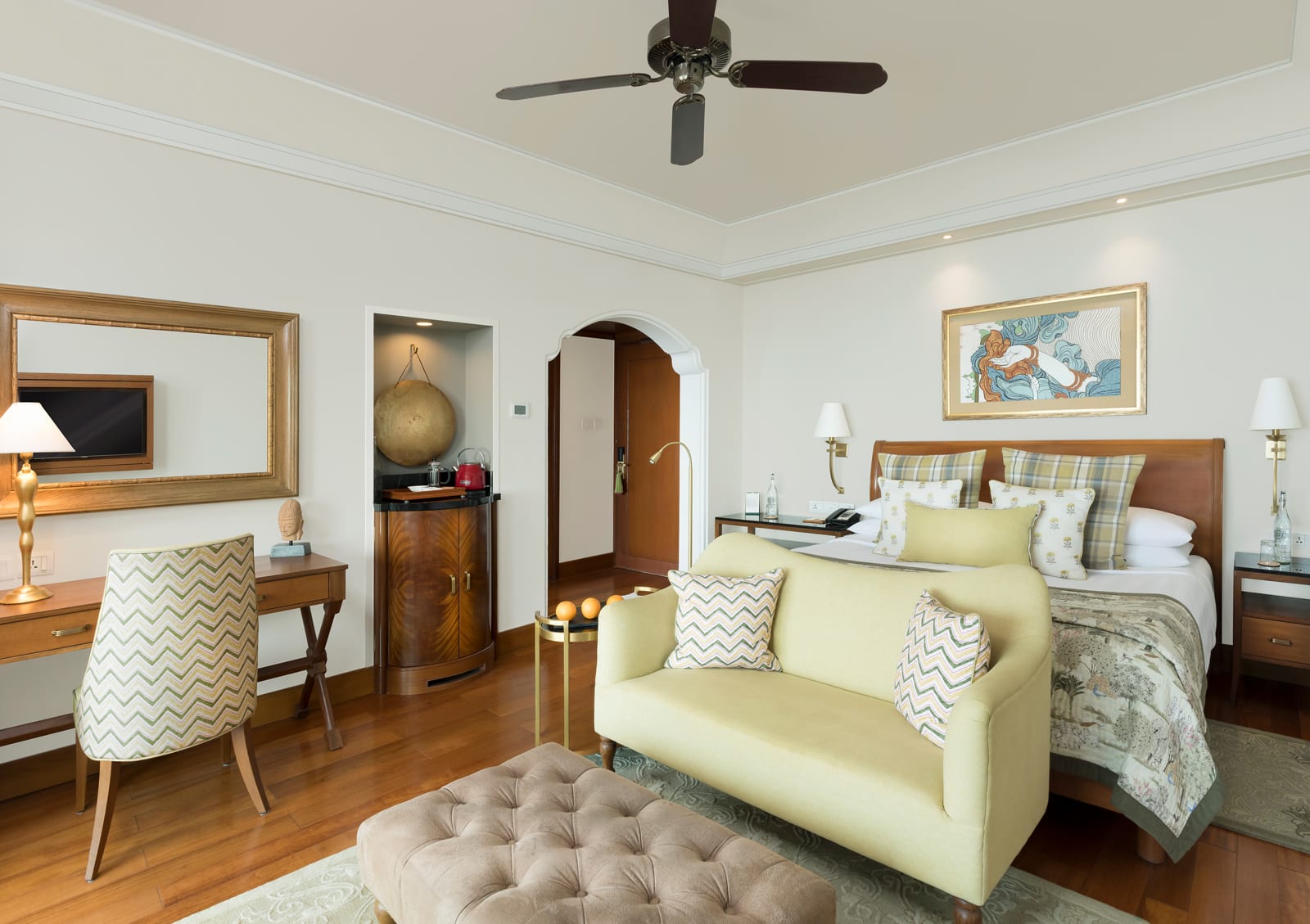 Living_Deluxe room 2 Luxury hotel bedroom with yellow sofa, wooden furniture, and ceiling fan overlooking bed
