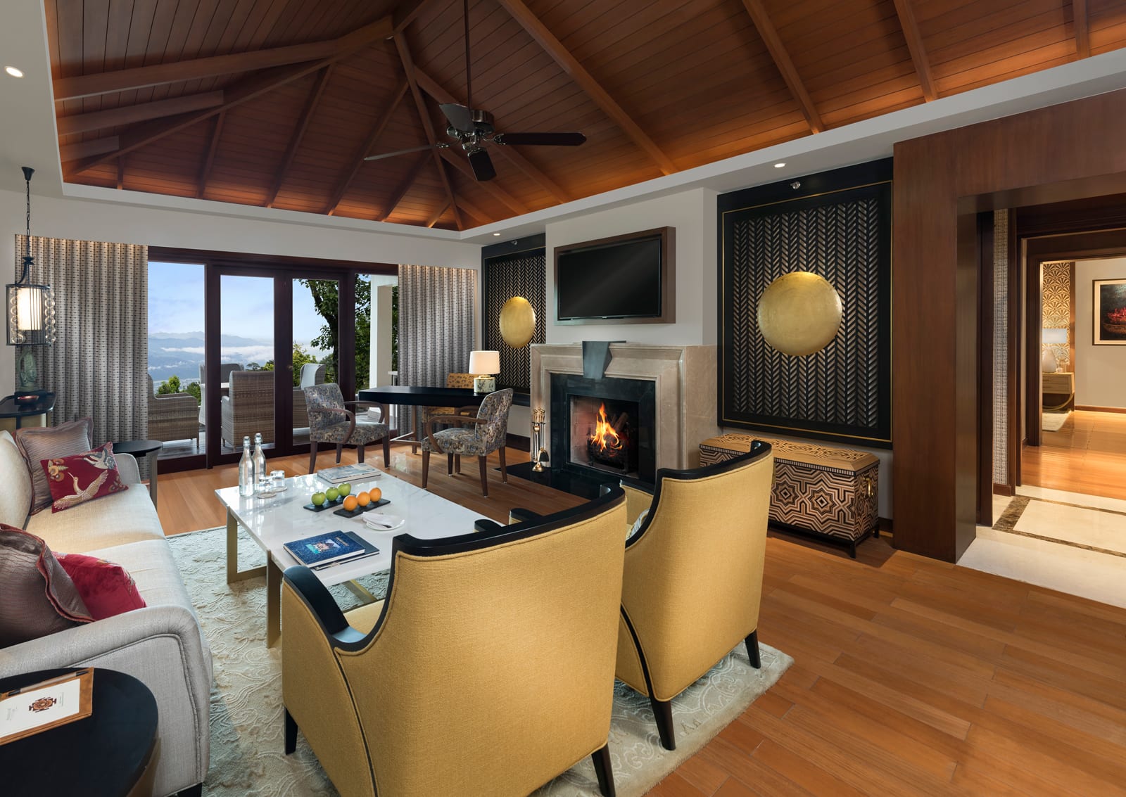 Living_Villa living room 1 Modern luxury living room with fireplace, yellow accent chairs, and wood vaulted ceiling overlooking lake