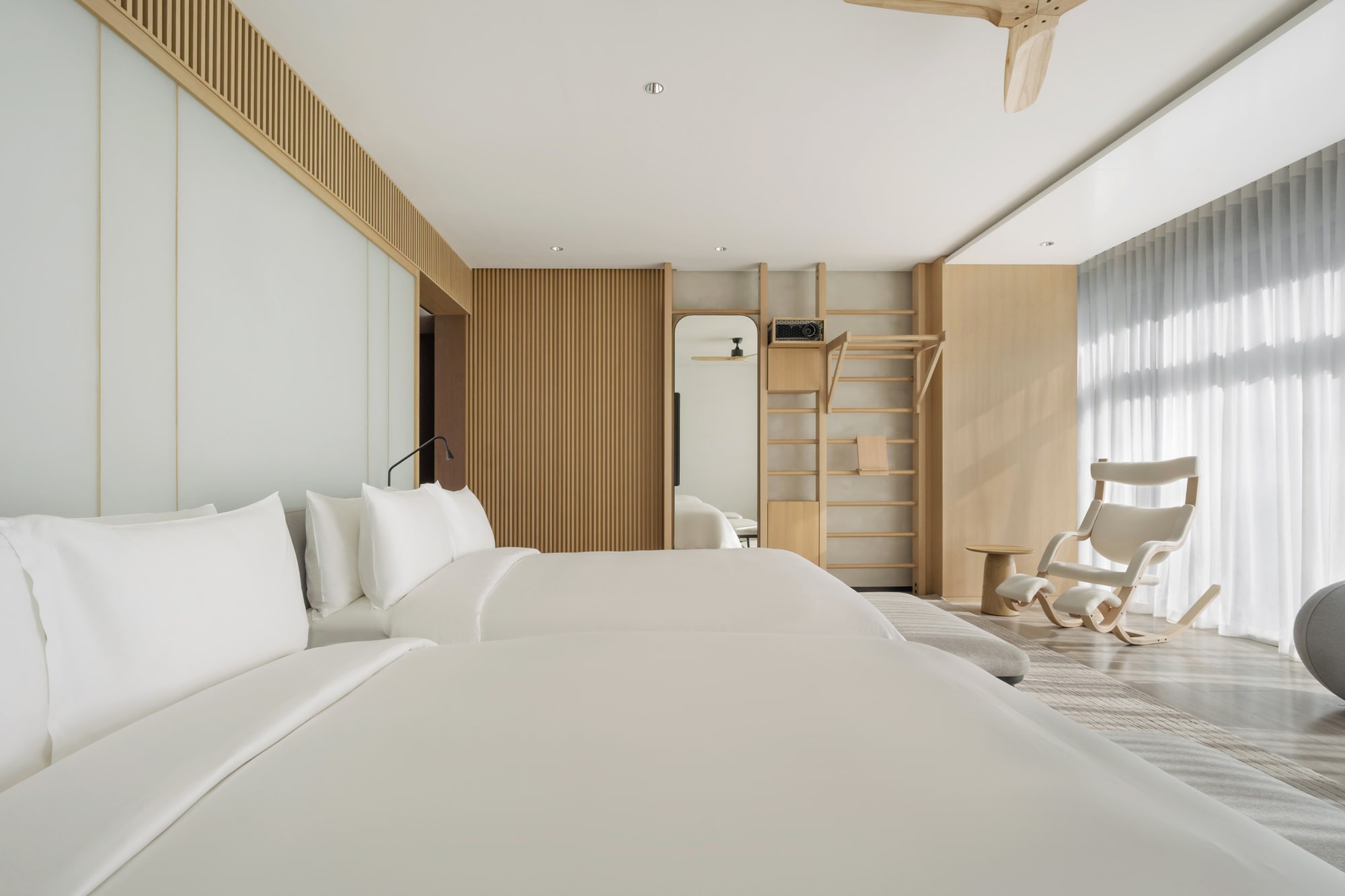 Siro Hotels Dubai Modern bedroom with white bed, wooden slat accent wall, and natural light from large windows