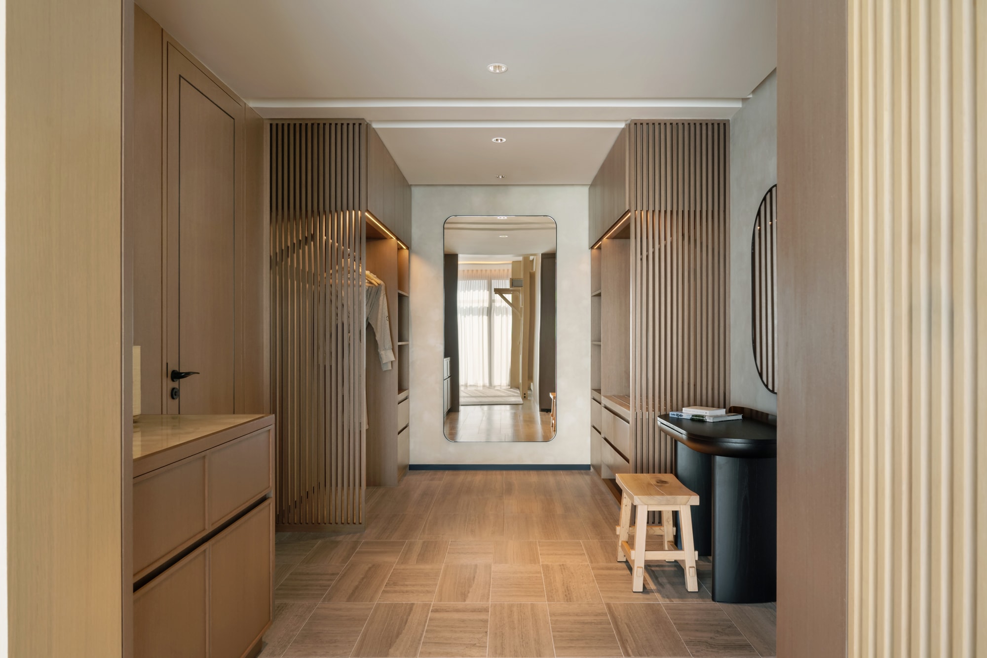 Siro Hotels Dubai Modern walk-in closet with wood cabinetry, vertical slat dividers, and central mirror
