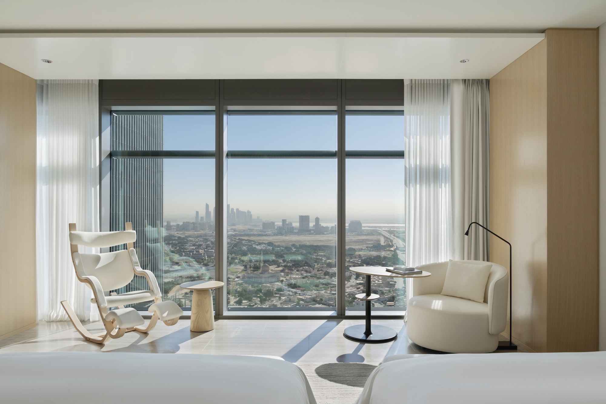 Siro Hotels Dubai High-rise hotel room with floor-to-ceiling windows overlooking city skyline and cream furnishings