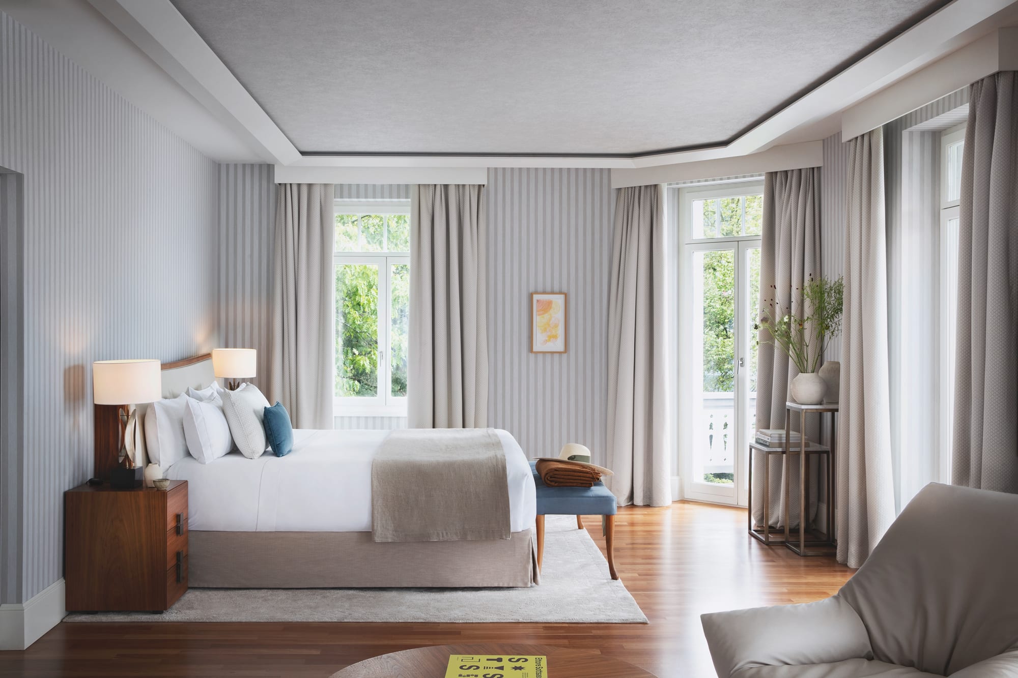 Suite (1) Luxury hotel bedroom with striped wallpaper, large windows, and wooden flooring