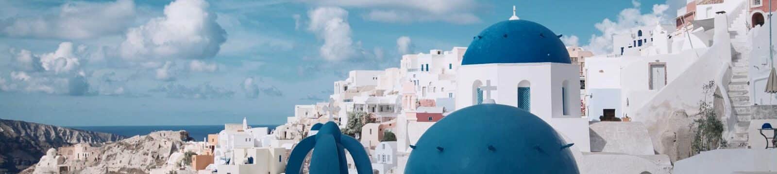 Santorini whitewashed buildings with iconic blue domed churches overlooking the Aegean Sea