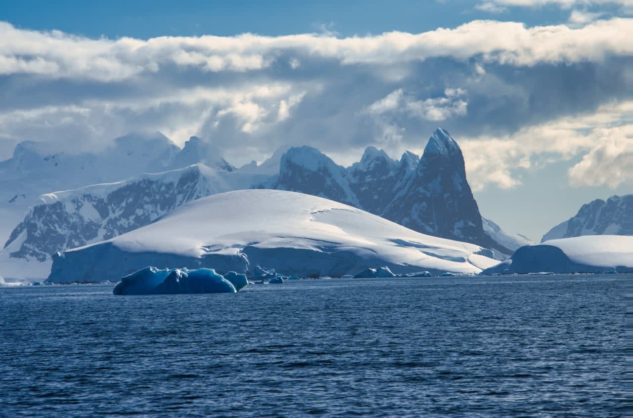 Antarctic Peninsula: Snowy peaks, icebergs, cloudy sky. Lemaire Channel Antarctic Peninsula